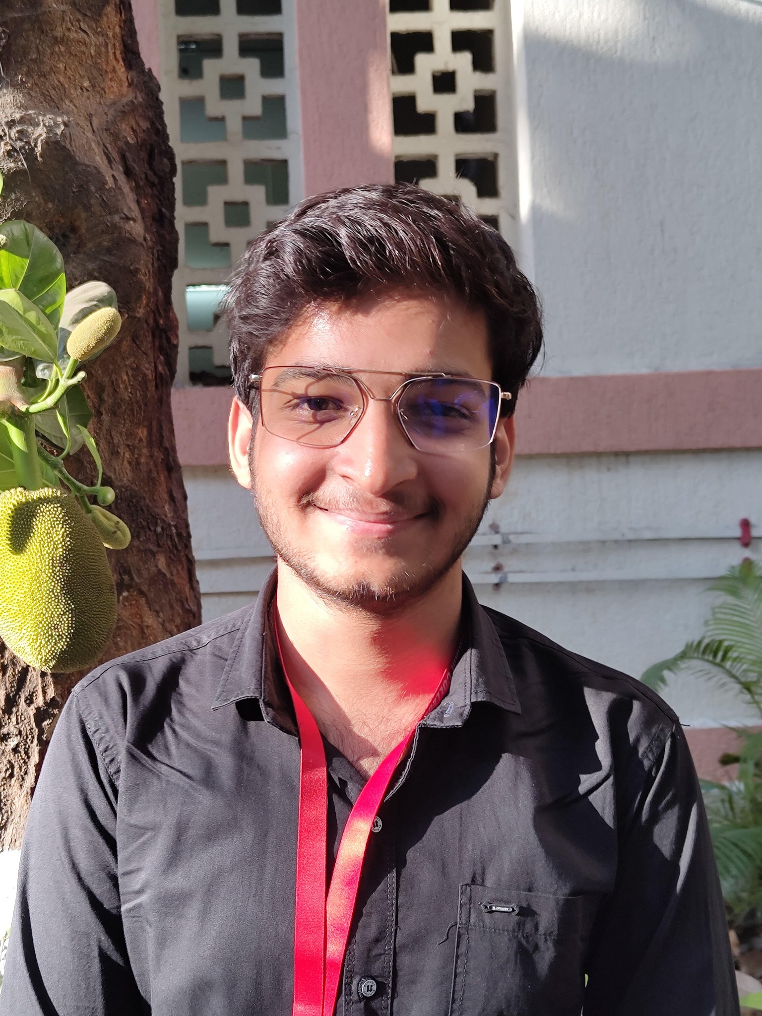 A smiling outdoor portrait wearing glasses and a black shirt